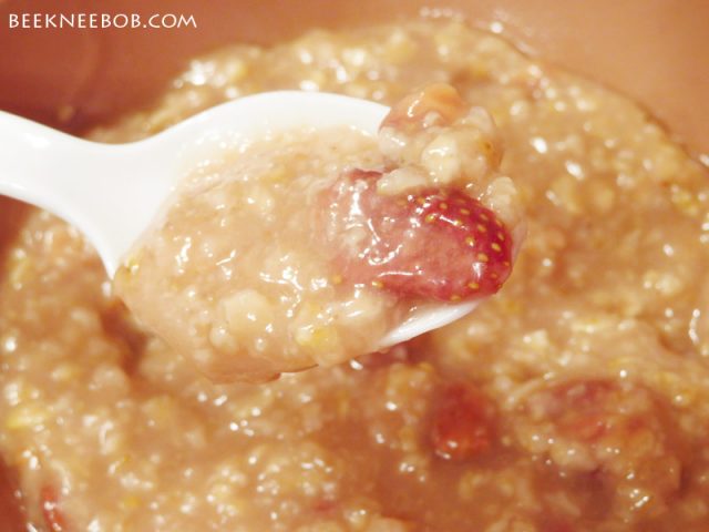 A spoonful of strawberry oatmeal hovering over a full bowl